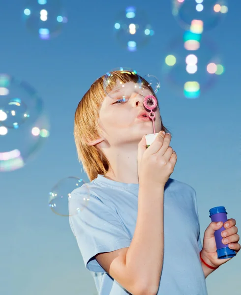 Menino com bolhas de sabão contra um céu — Fotografia de Stock