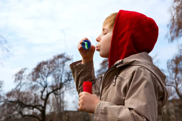 Boy with soap bubbles against a sky — Stock Photo, Image