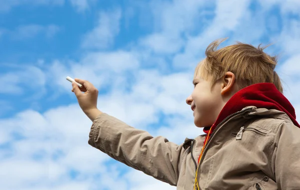 El niño dibujando una tiza en el cielo nublado — Foto de Stock