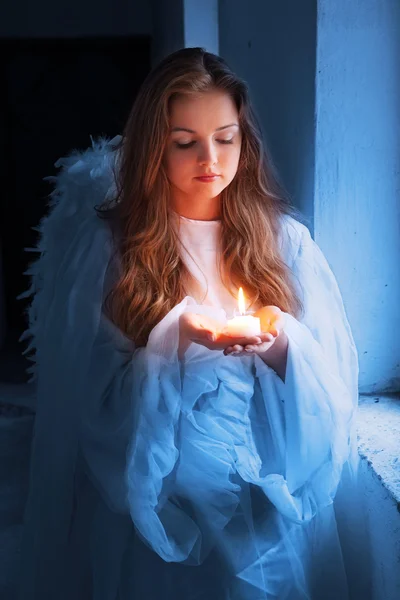 Retrato de un ángel con una vela de pie cerca de la ventana . — Foto de Stock