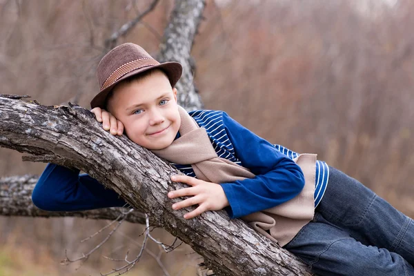 Улыбающийся мальчик лежит на дереве . — стоковое фото