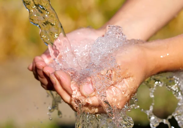 Женские руки с брызгами воды — стоковое фото