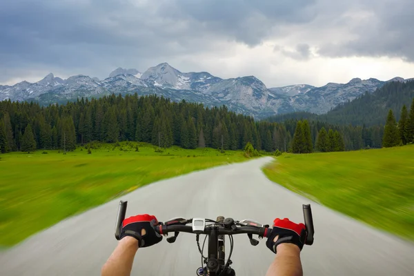 Man with bicycle riding mountain road — Stock Photo, Image