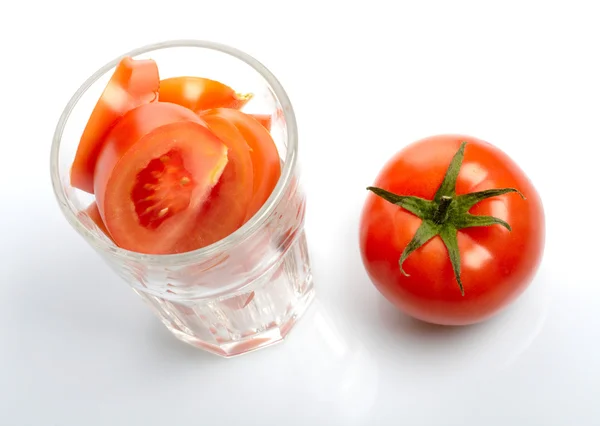 Tomaat en segmenten in glas geïsoleerd op witte achtergrond — Stockfoto