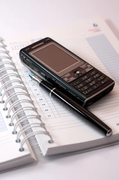 Telefon a pera leží na deník na bílém pozadí — Stock fotografie