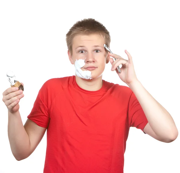Der Junge, der Teenager versucht zum ersten Mal eine Rasur und ist verwirrt. — Stockfoto