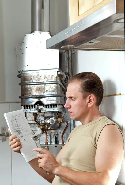 Чоловік з ключем думає про ремонт газового водонагрівача — стокове фото