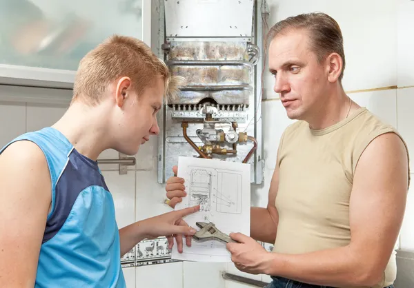O pai e o filho-adolescente em conjunto olham a instrução no reparo um g — Fotografia de Stock