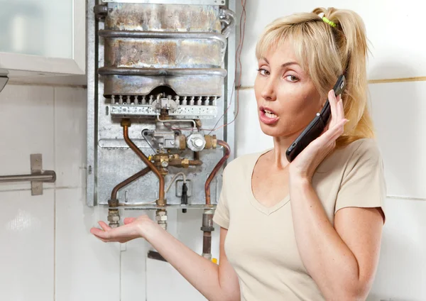 Молодая женщина домохозяйка звонит в мастерскую по ремонту газовой воды — стоковое фото