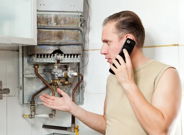 L'homme appelle par téléphone pour provoquer le réparateur de chauffe-eau à gaz — Photo