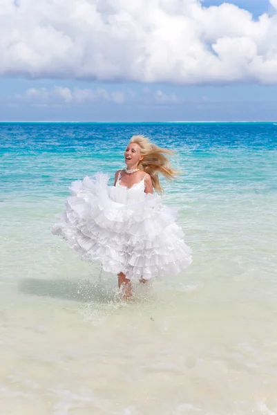 La bella donna giovane in un vestito della sposa corre su onde del mare — Foto Stock