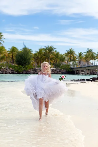 A bela mulher jovem em um vestido da noiva corre em ondas do mar — Fotografia de Stock