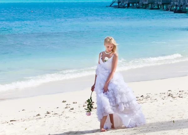La mujer joven hermosa en el vestido de la novia que se encuentra al borde del mar —  Fotos de Stock