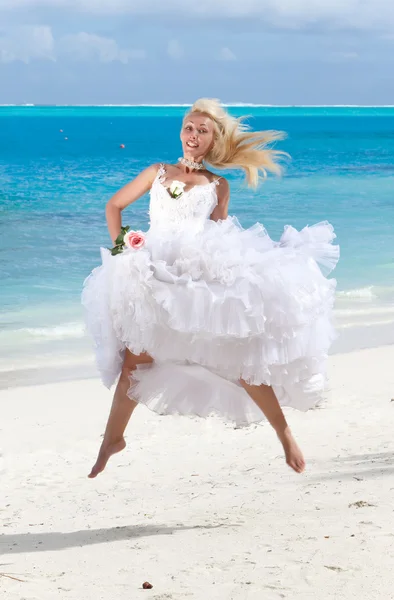 The young beautiful woman in a dress of the bride jumps at sea edge. — Stock Photo, Image