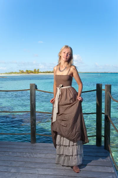 La joven hermosa mujer con una rosa en un camino de madera en el mar, trópicos — Foto de Stock