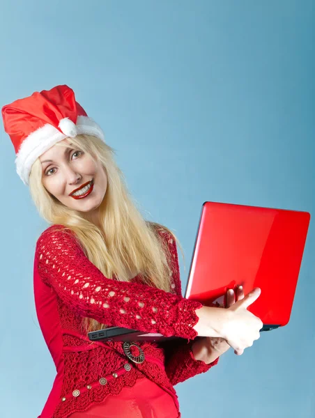 Blondýna v novoroční klobouku a s červeným laptop — Stock fotografie