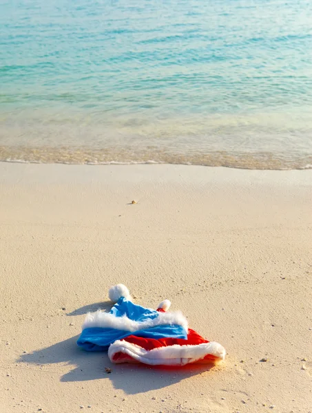 Две новогодние шапки Санта Клауса на пляже — стоковое фото