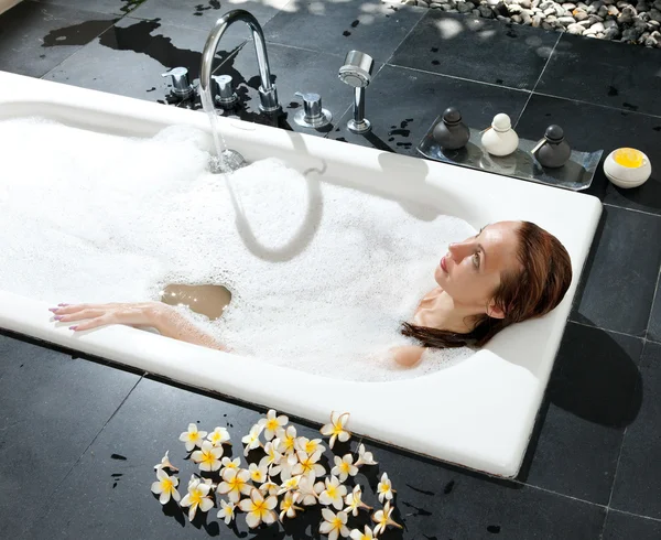 La mujer se acuesta en jabones en el baño, agua llena —  Fotos de Stock