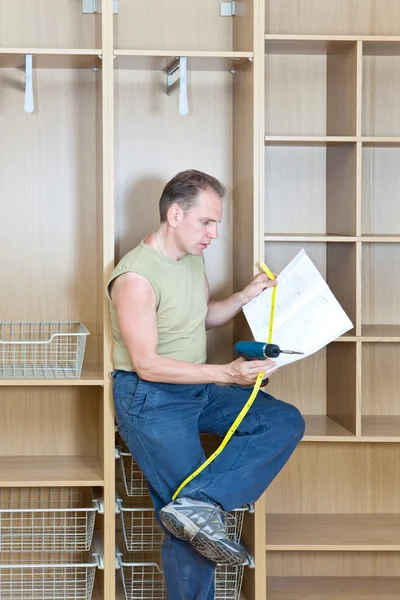 El hombre estudia la instrucción sobre el montaje de un nuevo armario — Foto de Stock