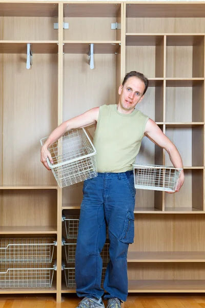 O homem estabelece cestos em um novo guarda-roupa — Fotografia de Stock