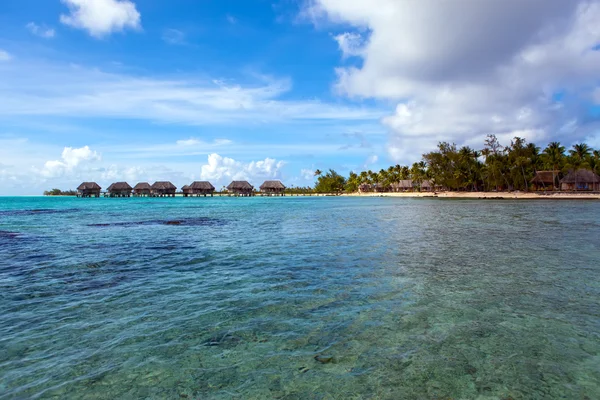 Vista na ilha tropical e pequenas casas no mar. Polinésia — Fotografia de Stock