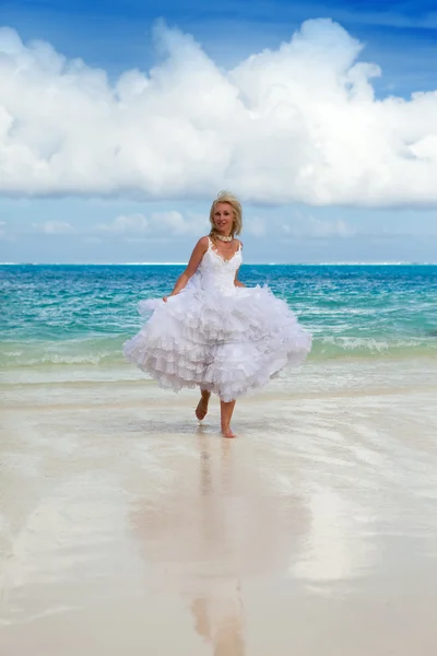 海の波に、花嫁のドレスの若い美しい女性が実行されます。 — ストック写真
