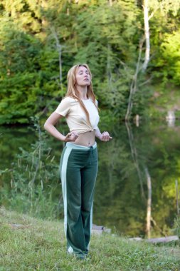 Young woman is engaged in sport on coast of pond