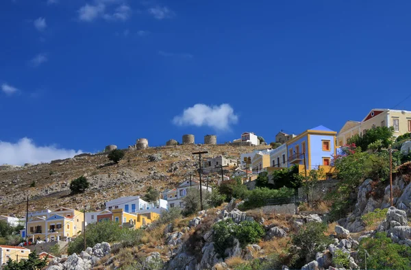 Grekland. dodecanesse. ön symi (simi). färgglada hus på stenar — Stockfoto