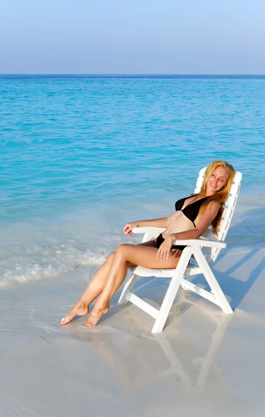 Joven bonita mujer tanes en silla de playa, puso en el océano —  Fotos de Stock