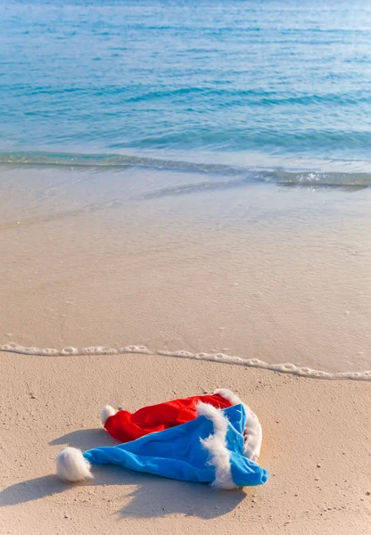 Two New Year's caps of Santa Claus on beach — Stock Photo, Image