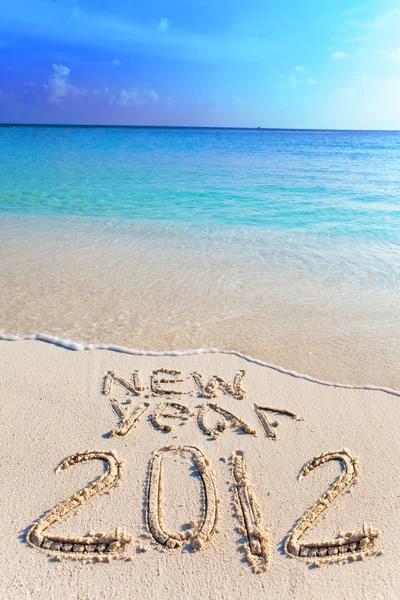 Na piasek na brzegu oceanu jest napisane "2012" — Zdjęcie stockowe