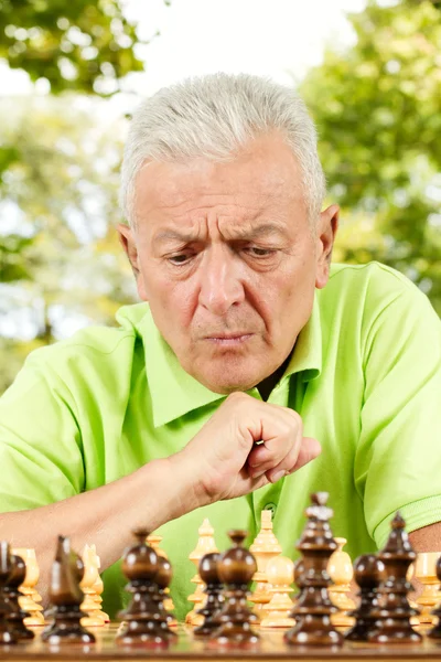 Портрет тривожного літнього чоловіка, який грає в шахи на відкритому повітрі — стокове фото