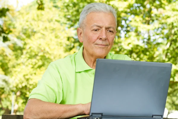 Senior man met laptop buiten — Stockfoto