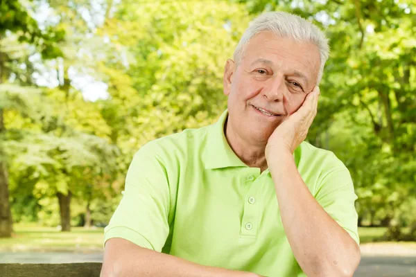 Portret uśmiechający się stary człowiek w parku — Zdjęcie stockowe