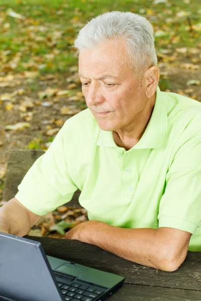 Senior man met laptop buiten — Stockfoto