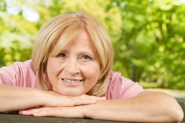Porträtt av leende senior kvinna i parken — Stockfoto