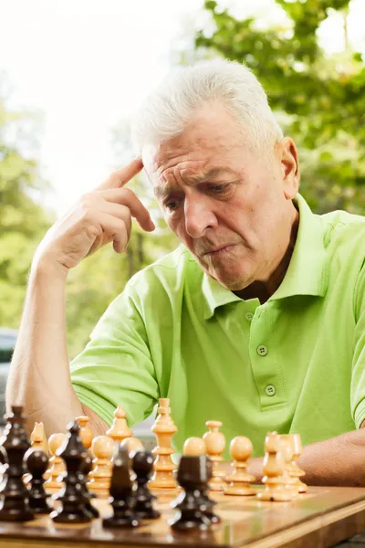 Пожилой человек думает о следующих шагах в шахматах — стоковое фото