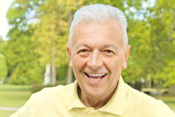 Portret van glimlachen senior man in het park — Stockfoto