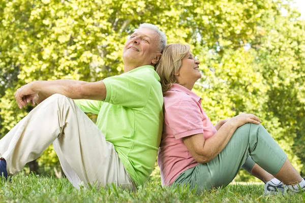 Feliz pareja de ancianos sentado en la hierba — Foto de Stock