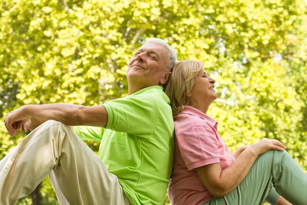 Щаслива старша пара сидить на траві — стокове фото