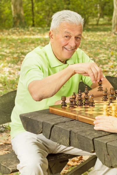 Elderly man playing chess in the park — Stock Photo, Image