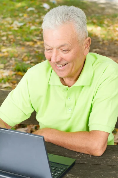 Пожилой человек с ноутбуком на улице — стоковое фото
