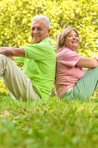 幸福的高级情侣坐在草地上 — 图库照片