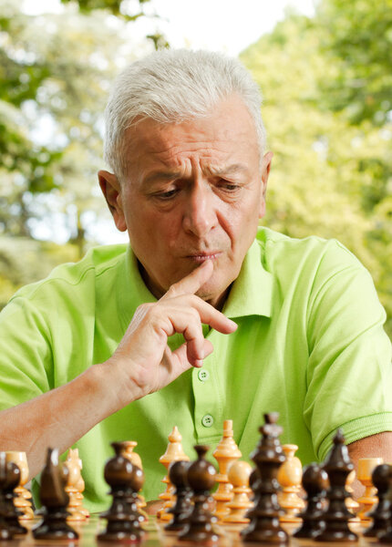 Portrait of worried elderly man playing chess outdoors