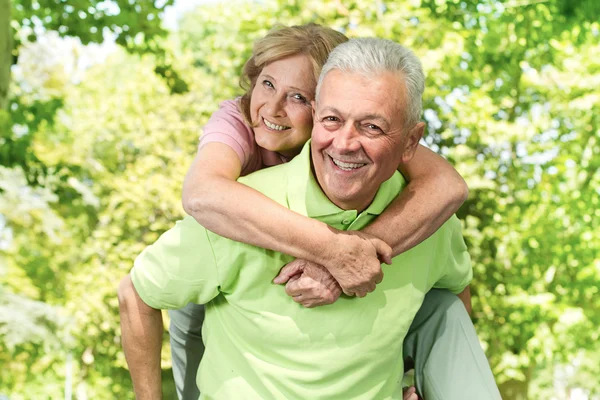 Senior lycklig ger piggyback ride — Stockfoto