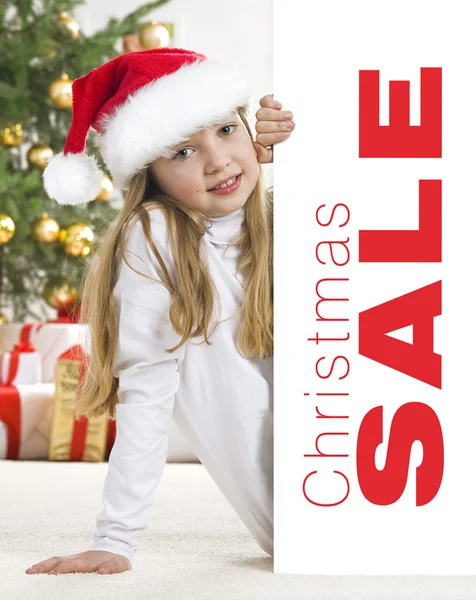 Young blonde girl in santa hat and red comforter behind white bo — Stock Photo, Image