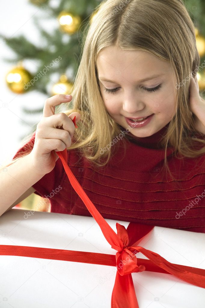 Beautiful teenage girl opening her christmas present. Christmas