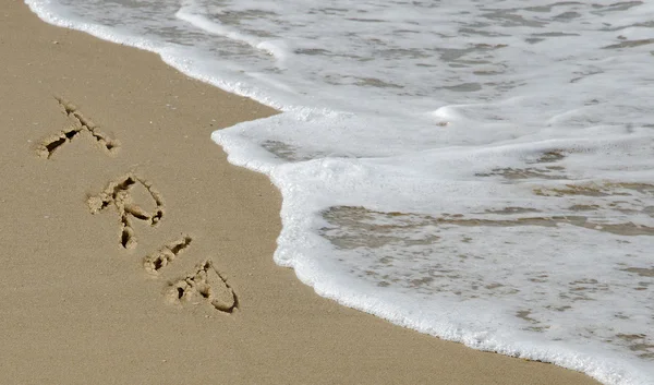 単語「旅」の海のビーチ上に描画 — ストック写真