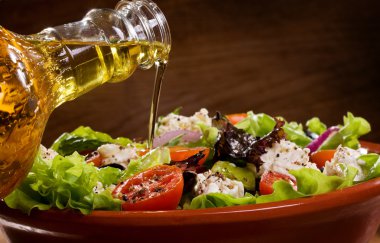 Vegetable salad with olive oil pouring from a bottle