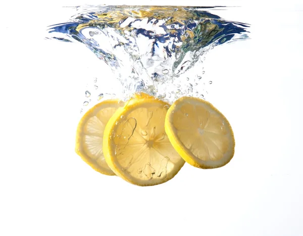 Lemon slices fall into water — Stock Photo, Image